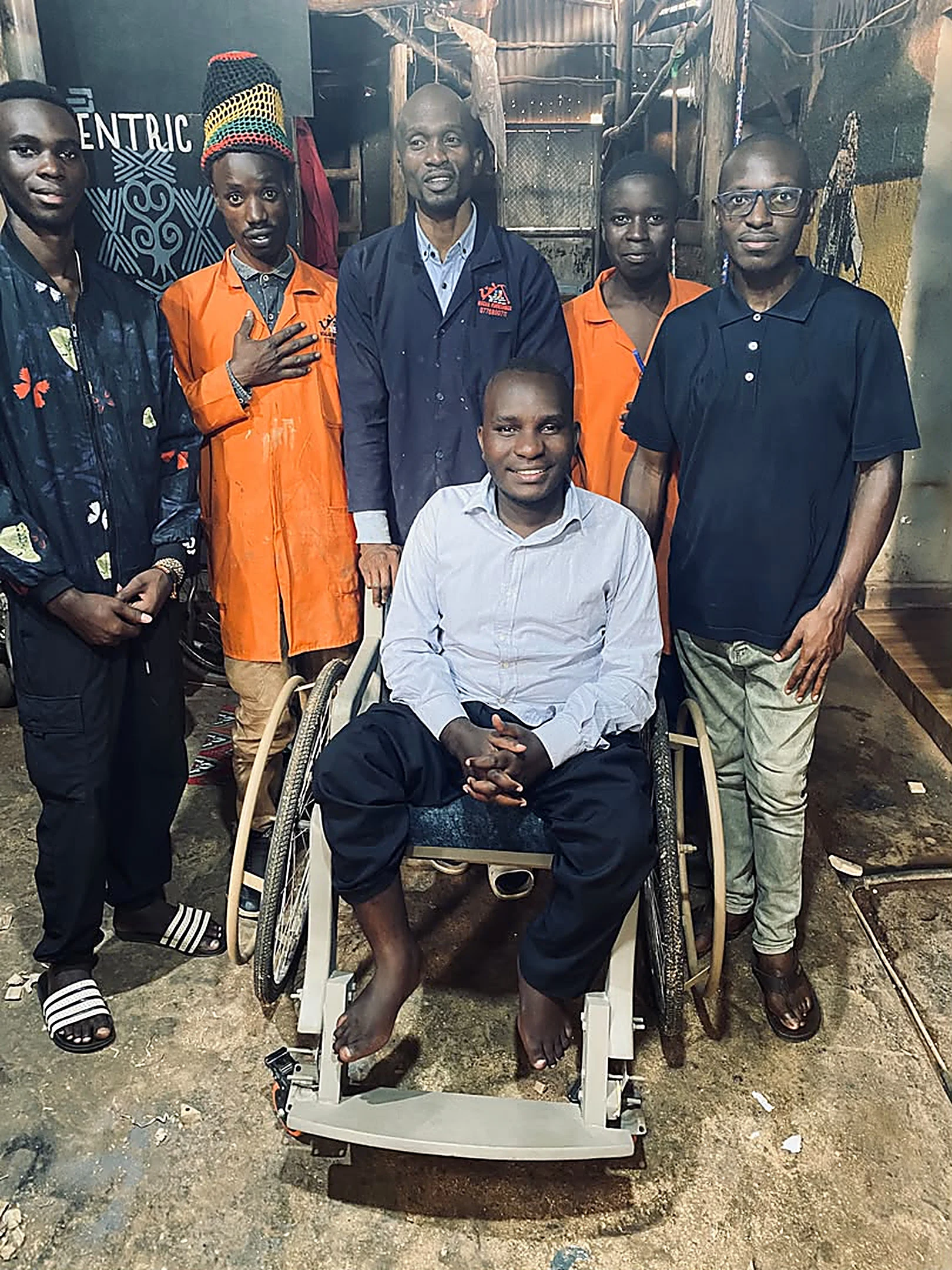 The Wheels of Equity workshop team standing behind a recipient in a finished wheelchair.